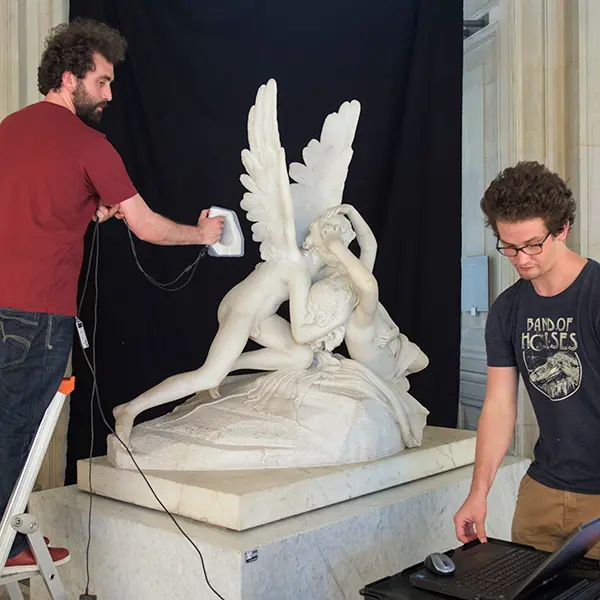 A view inside the Louvre Museum at the exhibition site for Psyche Revived by Cupid’s Kiss. Two operators from the GrandPalaisRmn photo agency are performing the 3D scanning. One of the operators is holding the 3D sensor while the second controls the ongoing process on a computer