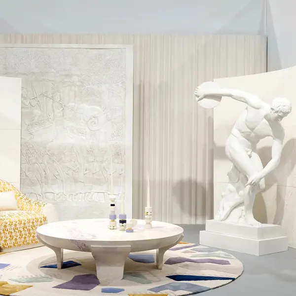 Vue large du stand des ateliers et de l’agence d’architecture d’intérieur Girodroux & Delpy au Salon « Révélations » 2024. On y voit des créations contemporaines : deux totems et une table basse avec un Discobole au format de l’original et un bas relief Assyrien Monumental. Dans le fond, deux paravents en stuc créés pour l’occasion