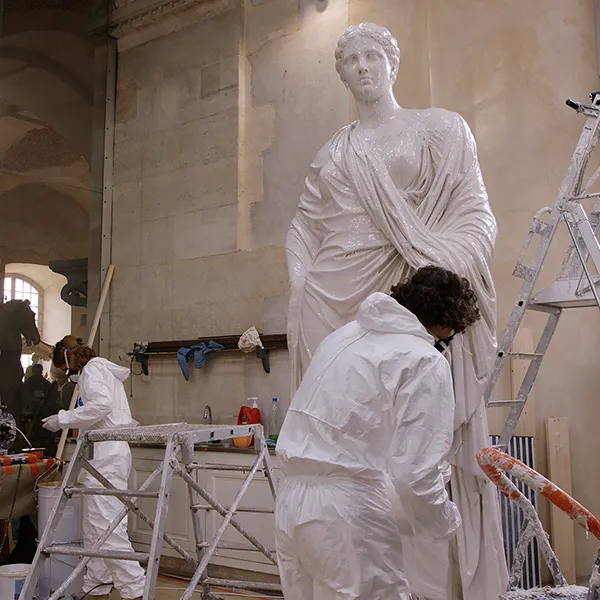Photo taken in the storage facilities of the Palace of Versailles. Wide shot of our two artisans preparing the original sculpture for a molding