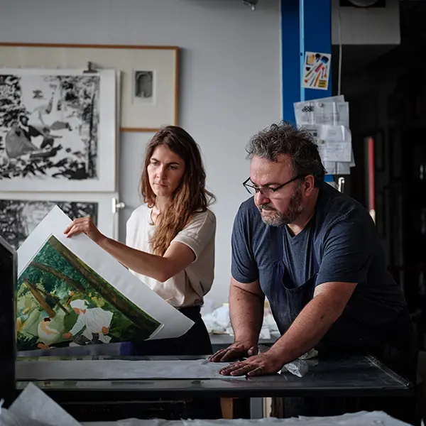 A shot in the Chalcographie du Louvre workshop. Lucile Vanstaevel and Bertrand Dupré are around the press. Lucile is holding a sheet on which a part of the colors of The Luncheon on the Grass is printed. They are both about to add a new color.
