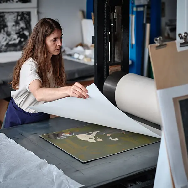 Vue dans l’atelier. Notre artisan place une feuille sur la plaque en vue de l’impression.