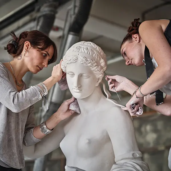 A shot in the cast workshop. Two artisans are working on the Venus of Arles at its original size