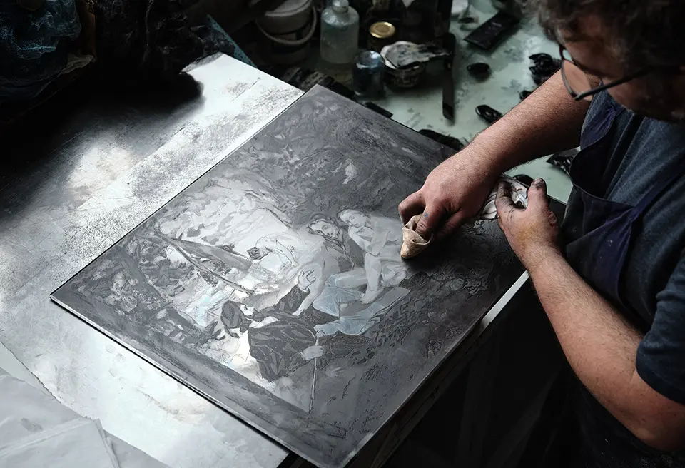 Gros plan sur le geste d'un artisant en train de retirer le surplus d'encre sur la plaque de cuivre du Déjeuner sur l’herbe d’après Édouard Manet (ref:KM006890)